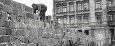 Uomo mette dei blocchi sul muro di Berlino